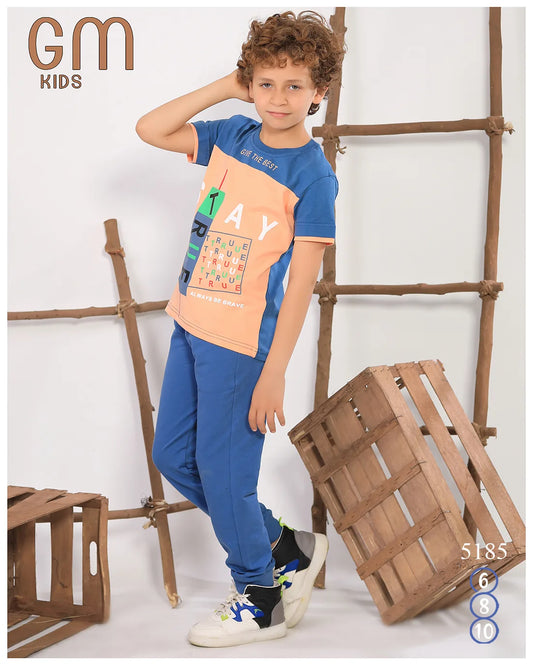 Child wearing a colorful t-shirt and blue pants standing in front of wooden crates.