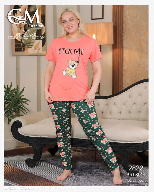 Woman wearing a pink 'Pick Me' t-shirt and green patterned pants in a room with a couch and lamp.