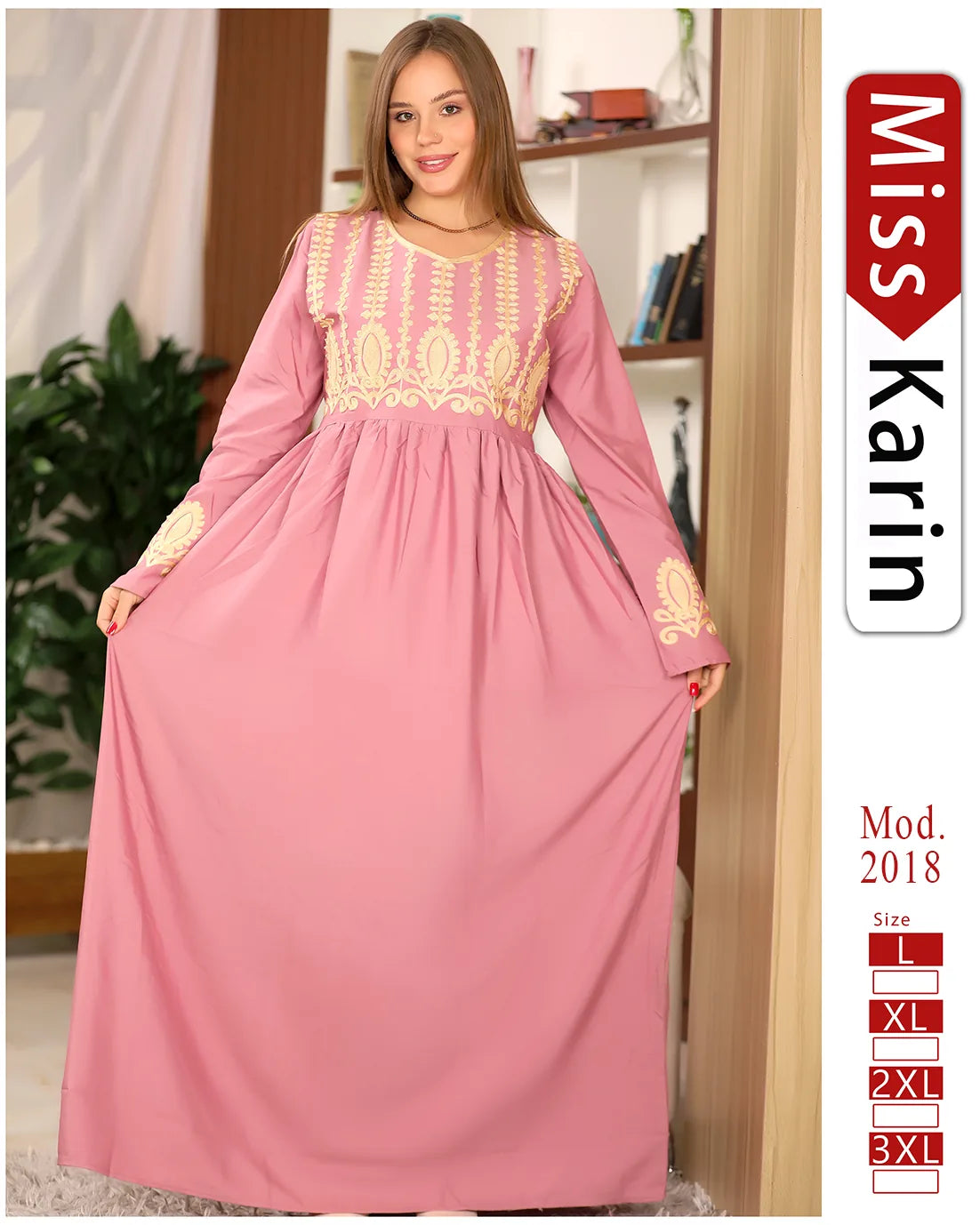 Woman wearing a pink dress with gold embroidery, standing indoors.