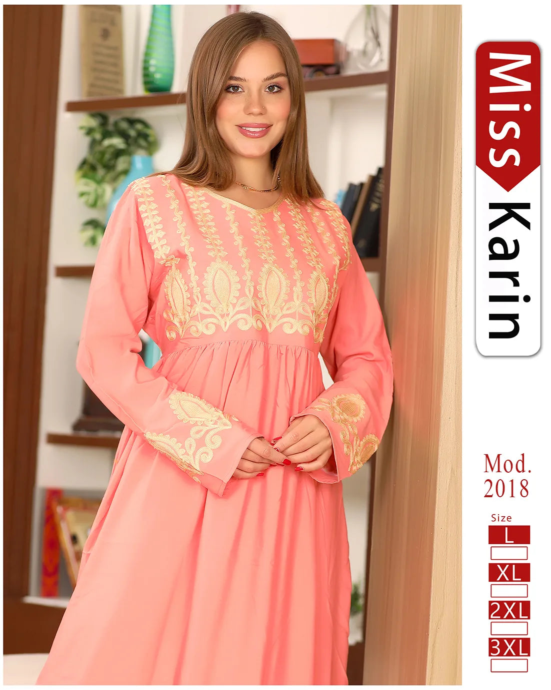 Woman wearing a pink dress with gold embroidery, standing indoors with a bookshelf in the background.