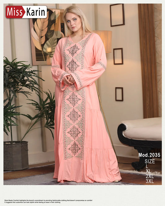 Woman wearing a pink embroidered dress in a room with decor elements.