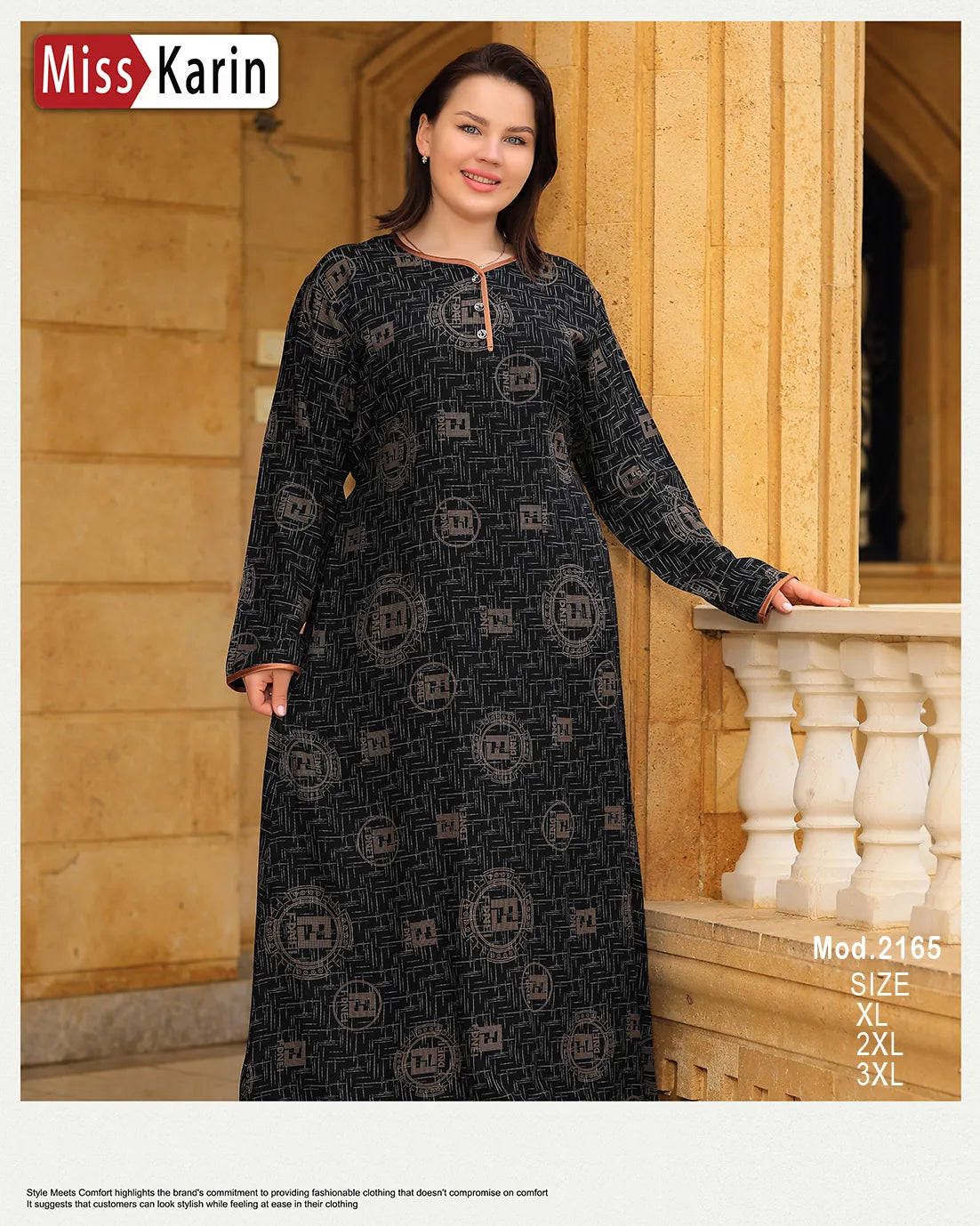Woman wearing a long black dress with patterns standing against a beige wall.