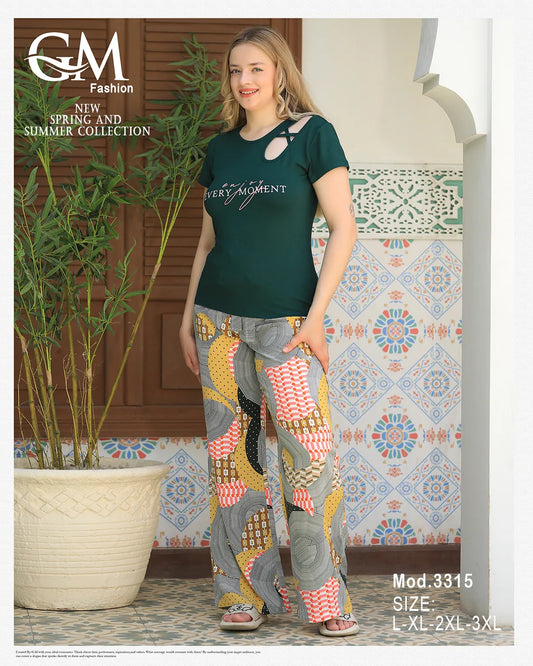 Woman wearing a green top and patterned pants standing in front of a decorative wall.