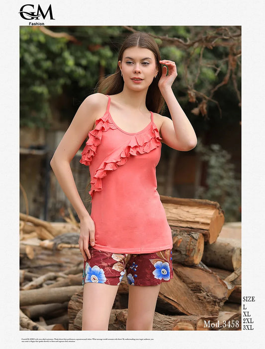 Woman wearing a coral ruffled top and floral shorts standing in front of wooden logs.