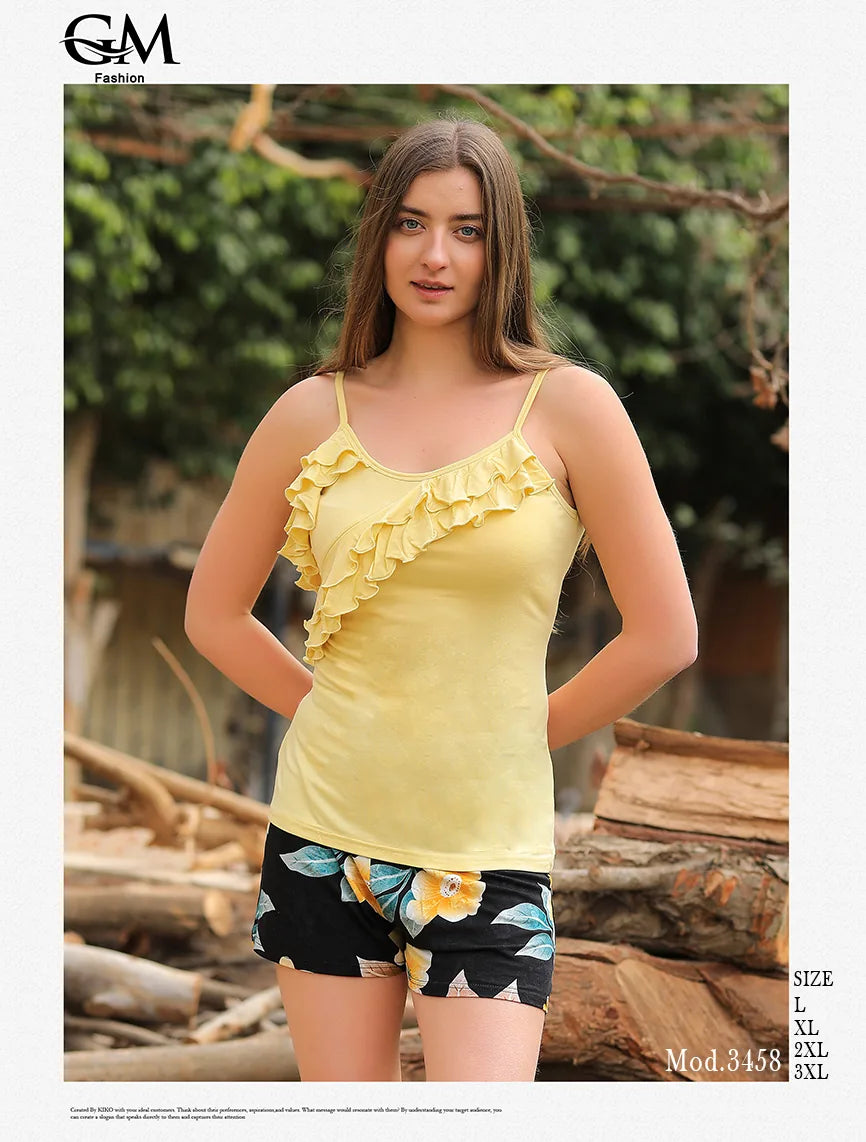 Woman wearing a yellow ruffled top and patterned shorts outdoors