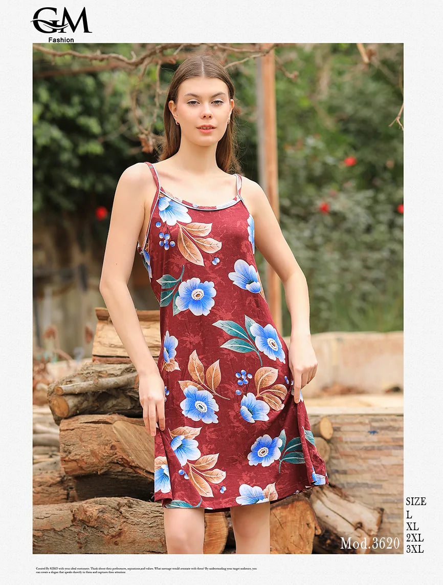 Woman wearing a floral dress standing outdoors with logs and greenery in the background
