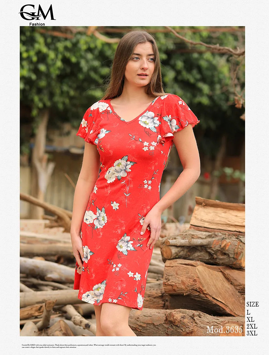 Woman wearing a red floral dress standing outdoors with wooden logs and greenery in the background.