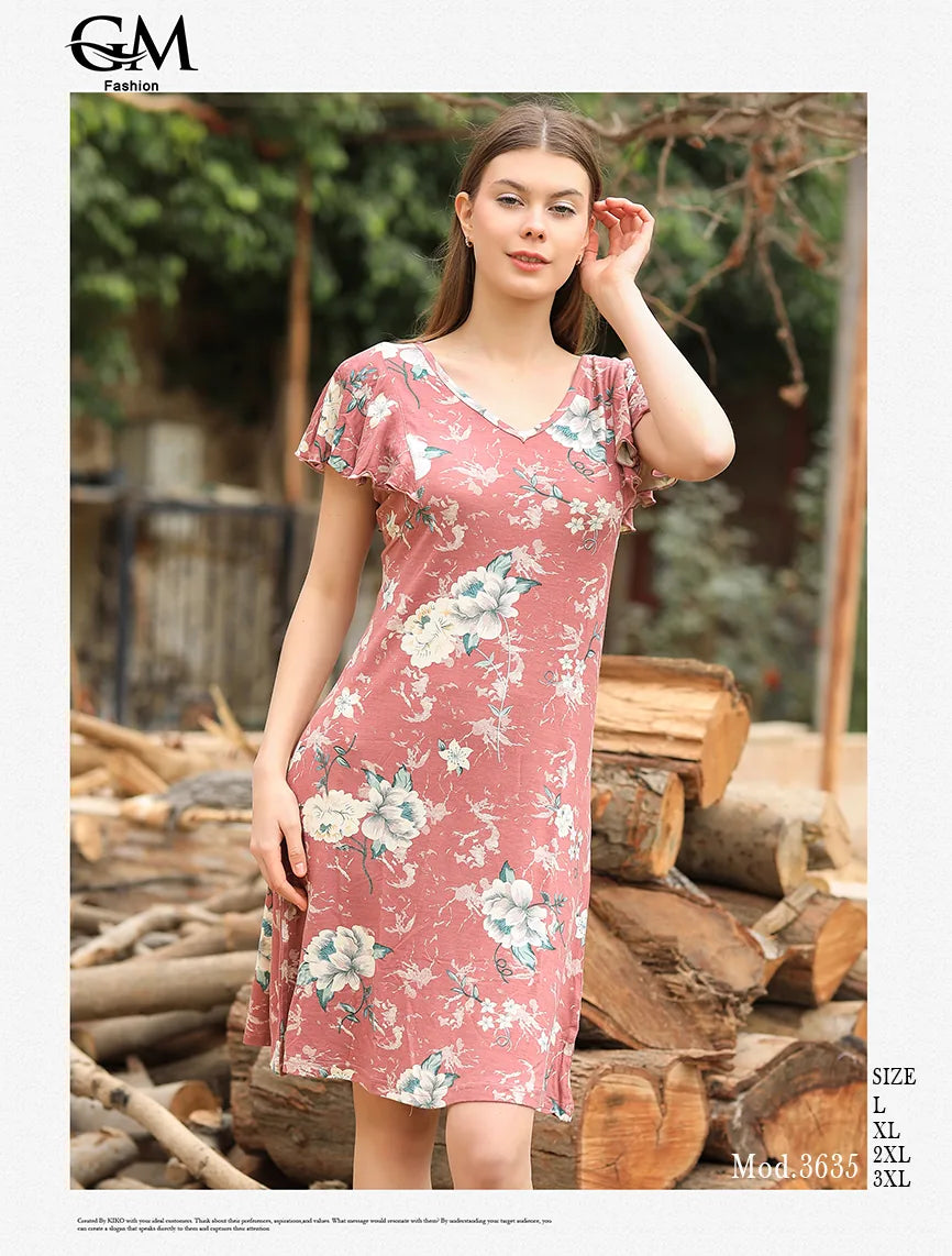 Woman wearing a pink floral dress standing among wooden logs with 'G&M Fashion' branding.
