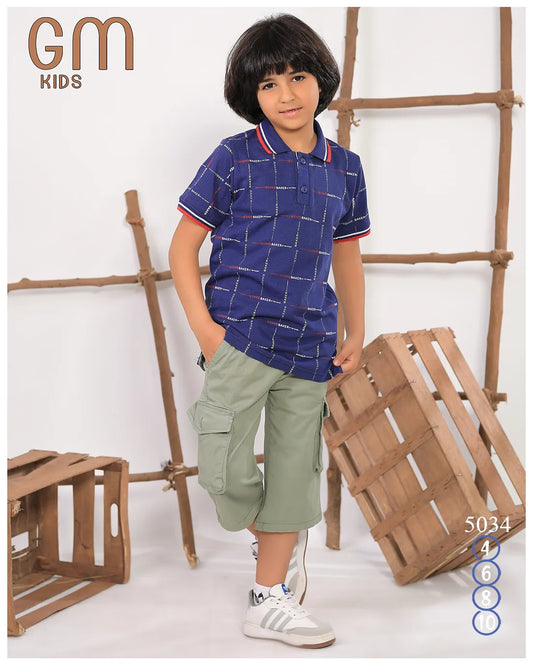 Child wearing a blue checkered shirt and green shorts with wooden crates in the background