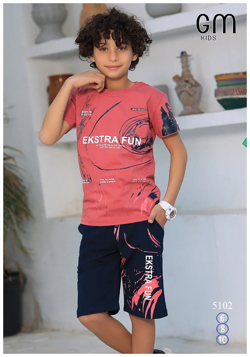 Child wearing a pink 'Ekstra Fun' t-shirt and navy shorts with matching design, standing indoors.