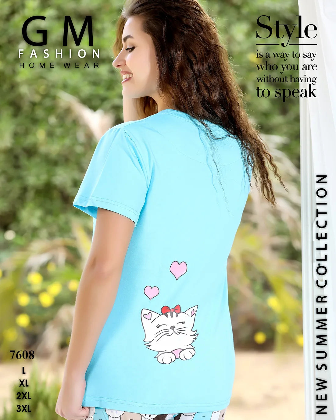 Woman wearing a light blue t-shirt with a cat design, standing outdoors with greenery in the background.