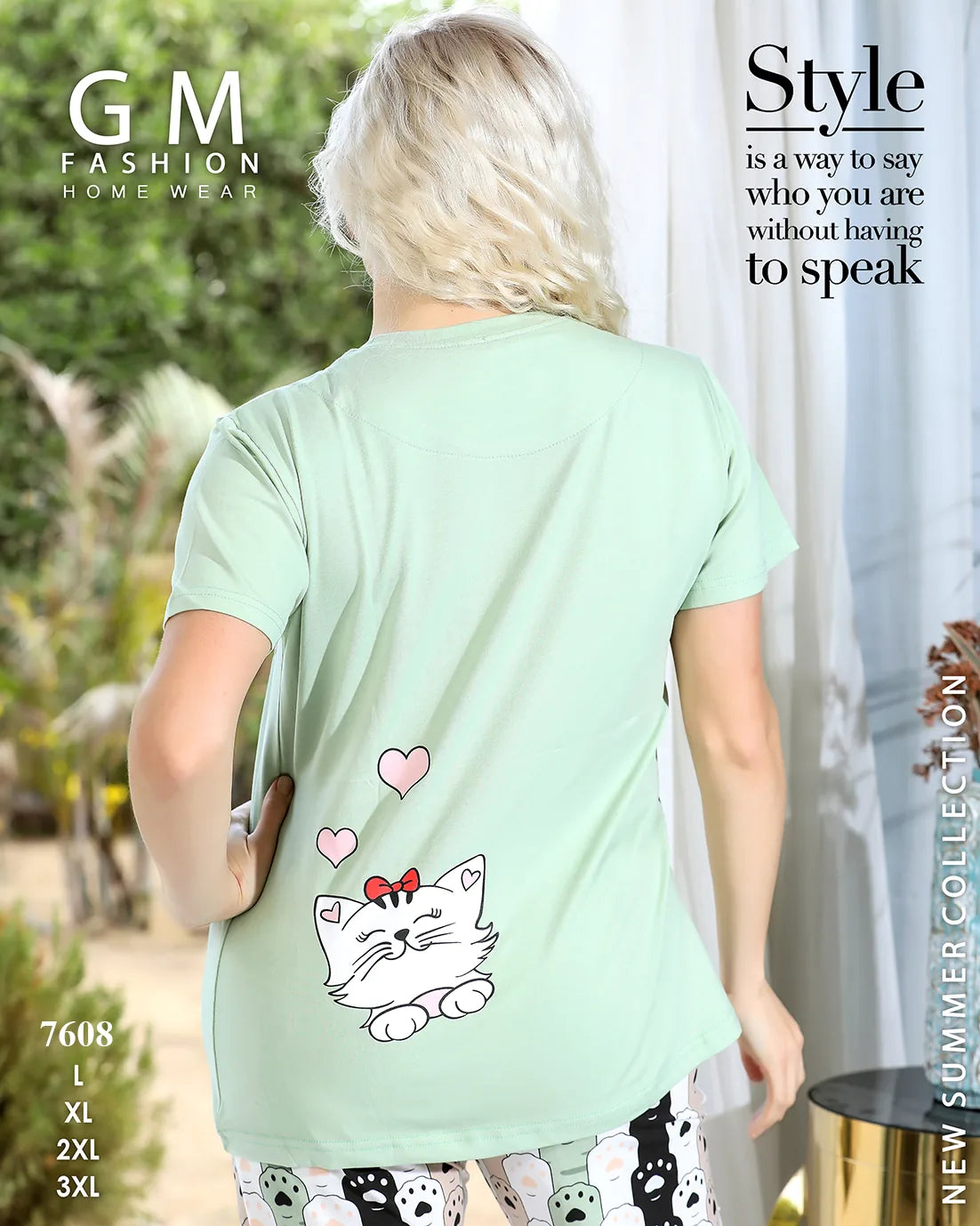Woman wearing a light green t-shirt with a cat design on the back, standing outdoors.