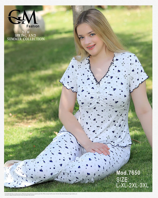 Woman wearing a white outfit with black patterns sitting on grass, with 'GM Fashion' branding.