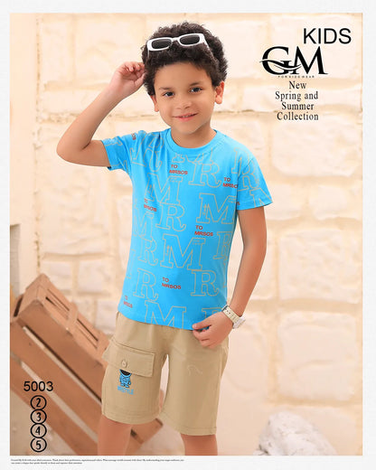 Child wearing a blue shirt and beige shorts with sunglasses on head, standing indoors.