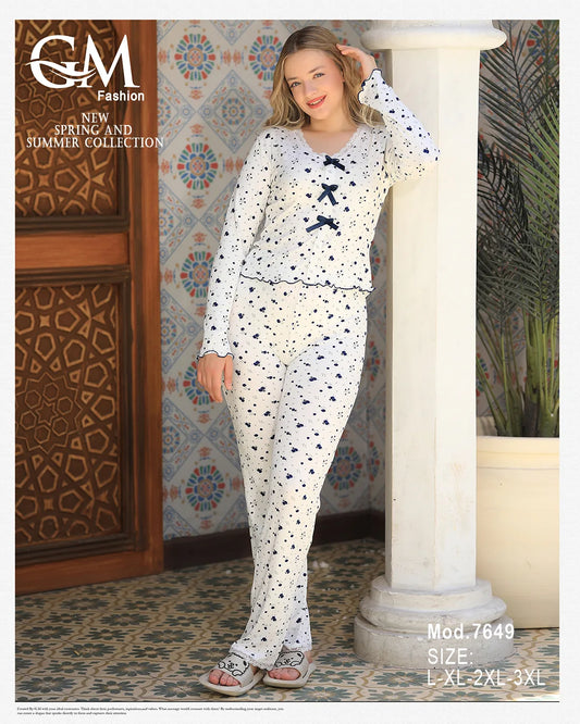 Woman wearing a patterned outfit by GM Fashion by a poolside with plants.