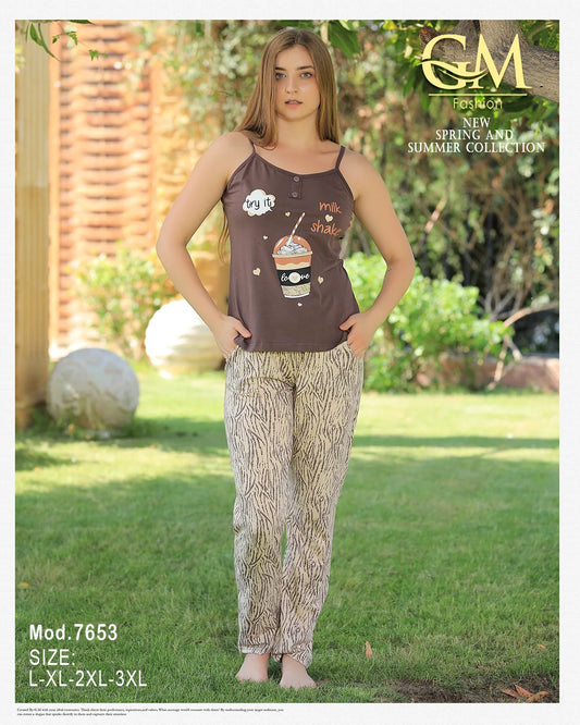 Woman wearing a brown tank top with a graphic design and patterned pants outdoors.