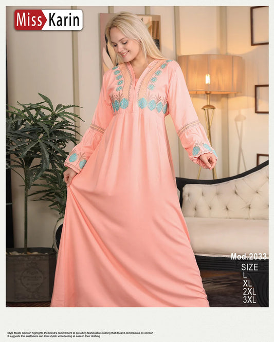 Woman wearing a pink dress with blue embellishments in a room setting, with 'Miss Karin' branding.