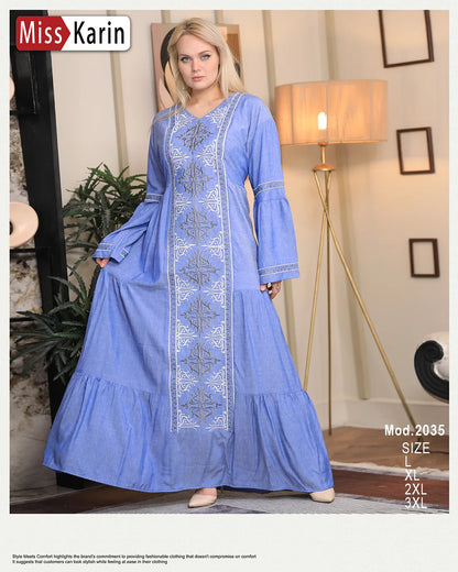 Woman wearing a blue dress with white embroidery in a room setting, featuring 'Miss Karin' branding.