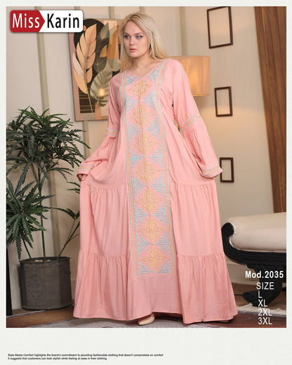 Woman wearing a pink dress with intricate patterns in a room setting, featuring 'Miss Karin' branding.