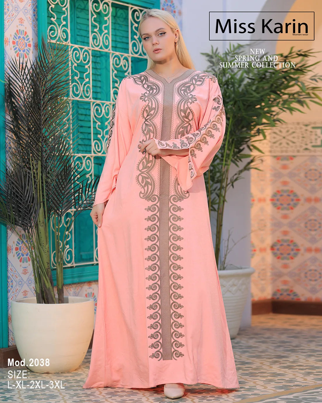 Woman wearing a pink embroidered dress with 'Miss Karin' branding in a decorative setting.