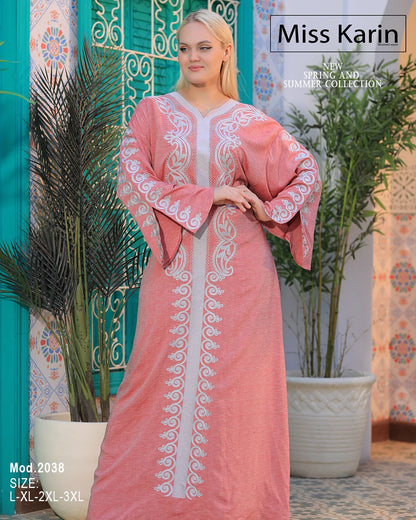 Woman wearing a pink dress with white embroidery in a decorative setting.