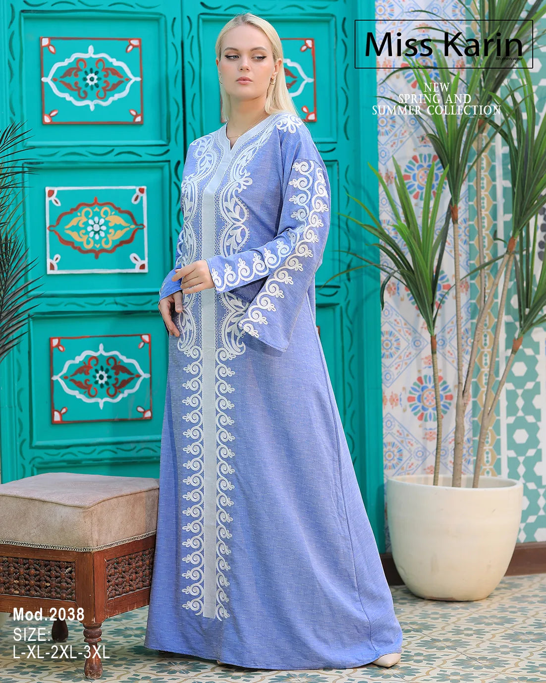 Woman wearing a blue embroidered dress with a decorative green wall in the background