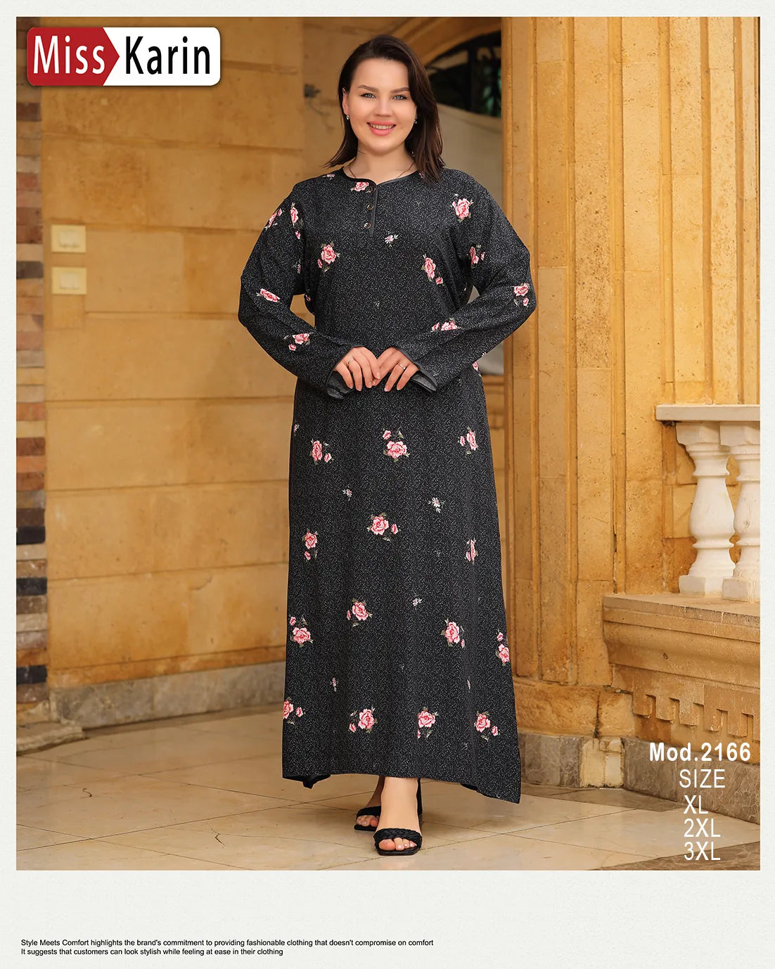 Woman wearing a black dress with pink floral patterns in front of a wooden building.