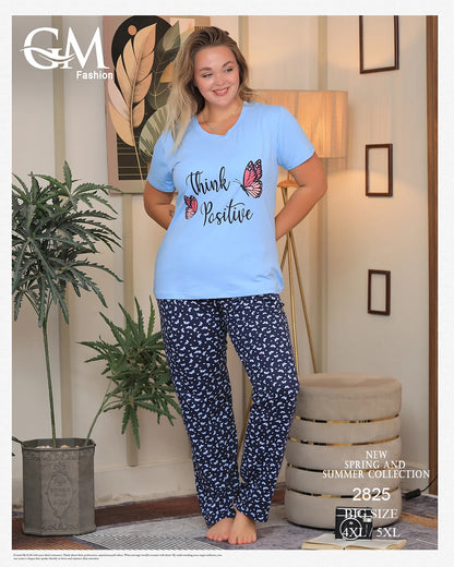 Woman wearing a light blue 'Think Positive' t-shirt and navy patterned pants in a home setting.
