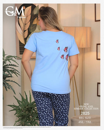 Woman wearing a light blue t-shirt with butterfly designs and dark blue patterned pants in a room setting.