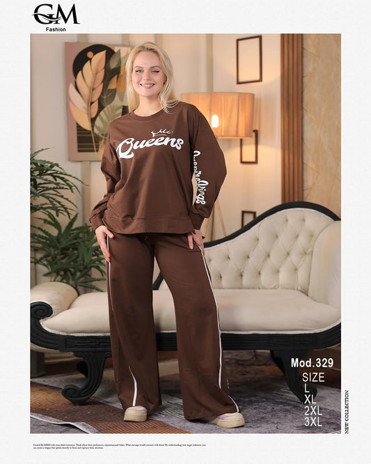 Woman wearing a brown outfit with 'Queens' text in a living room setting, featuring GM Fashion branding.