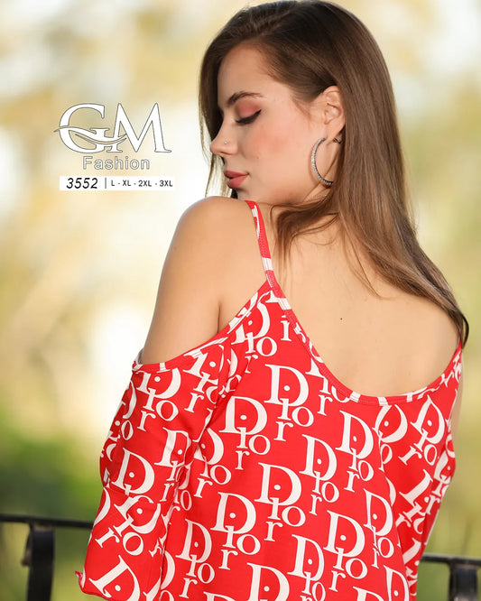 Woman wearing a red top with white lettering, standing outdoors with a blurred natural background.