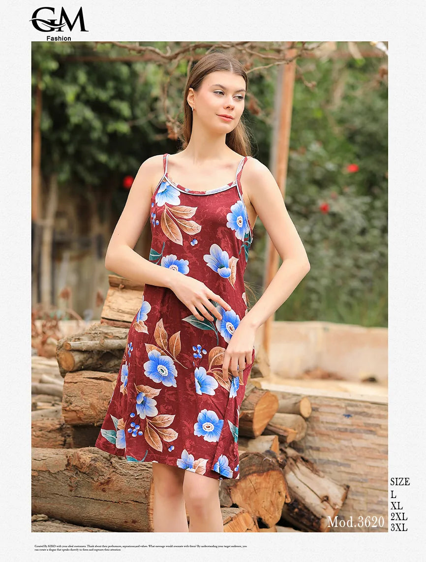 Woman wearing a floral dress standing outdoors with wooden logs and greenery in the background