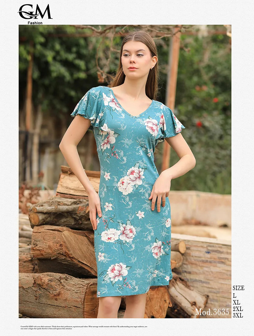 Woman wearing a floral dress standing outdoors with logs and greenery in the background