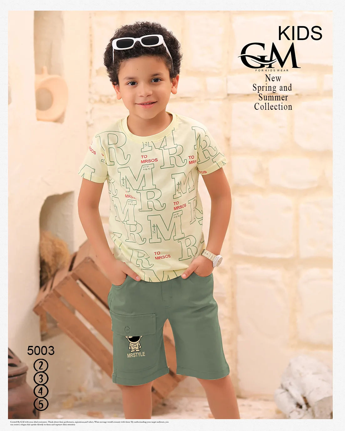 Child wearing a patterned shirt and green shorts with sunglasses on head, standing indoors.