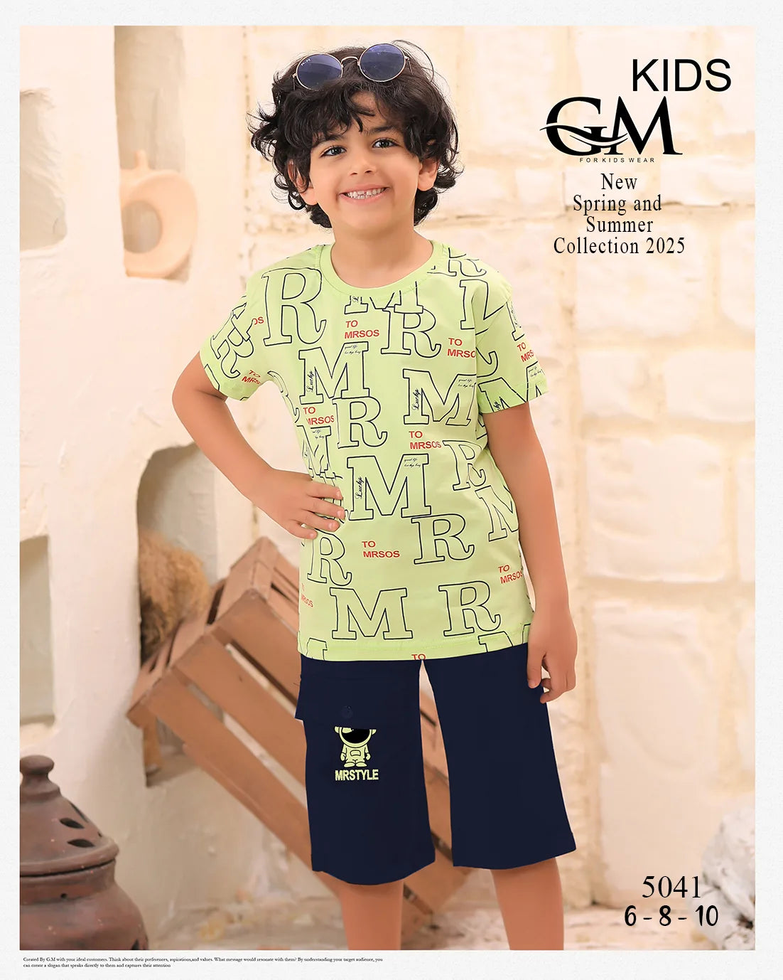 Child wearing a light green t-shirt with letter patterns and dark blue shorts, standing indoors.