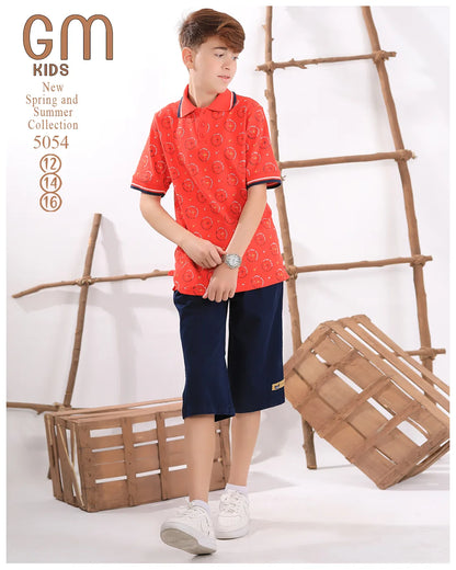 Child wearing a red patterned shirt and navy shorts standing next to a wooden ladder and crate.