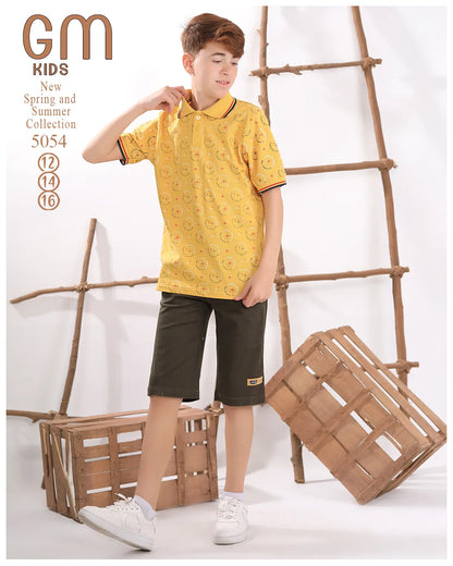 Child wearing a yellow shirt and green shorts standing next to wooden crates and a ladder.