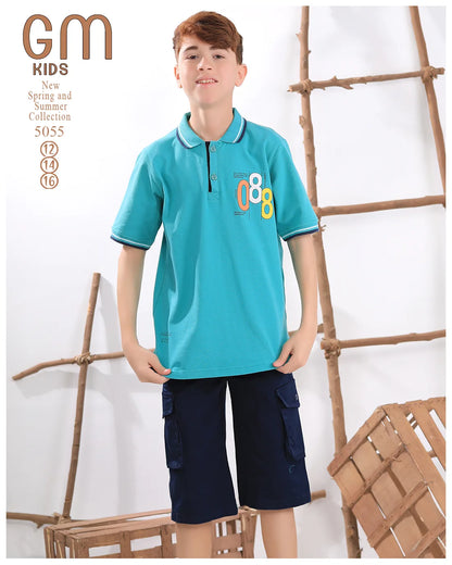 Child wearing a turquoise polo shirt with '88' design and navy shorts, standing against a white background with wooden decor.
