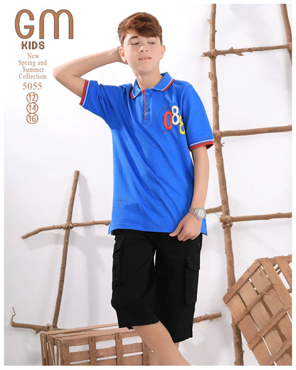 Child wearing a blue polo shirt with colorful numbers and black shorts, standing against a white background with wooden elements.