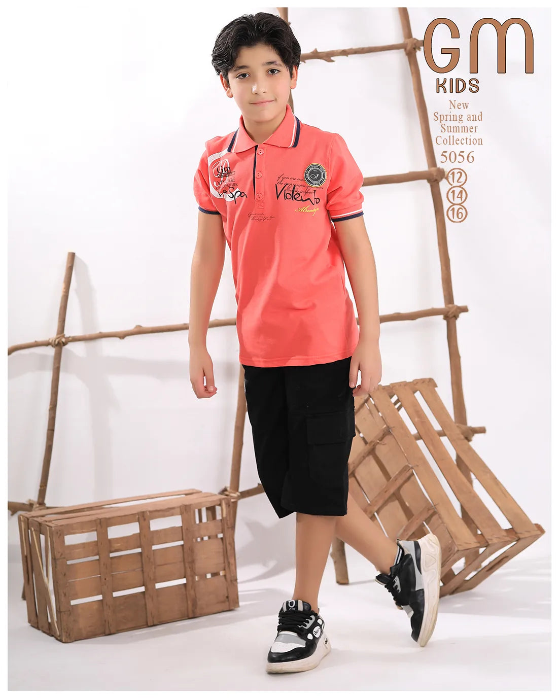 Child wearing a pink polo shirt with brand logo, black shorts, and sneakers against a white background with wooden crates.