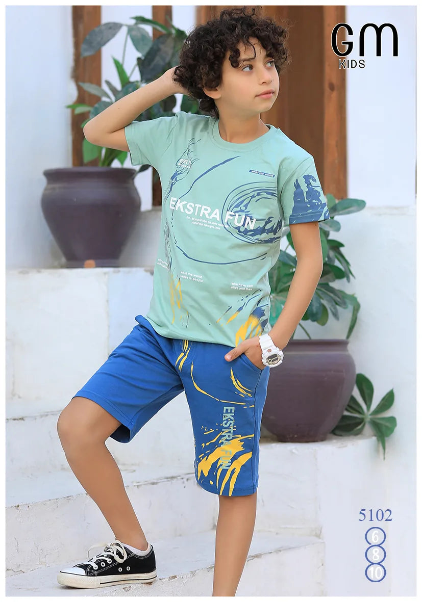 Child wearing a green t-shirt and blue shorts with 'Ekstra Fun' text, standing outdoors.