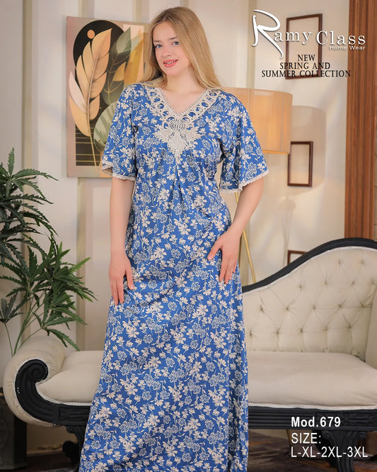 Woman wearing a blue floral dress in a room with a lamp and plant.