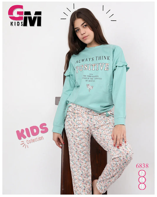 Girl wearing a teal sweatshirt with text and floral pants, standing against a white background with 'GM Kids' branding.