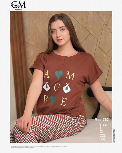 Woman wearing a brown t-shirt with decorative text and patterns, sitting against a beige wall.