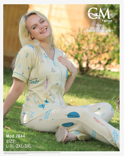 Woman in a floral dress sitting on grass with 'GM Fashion' branding.