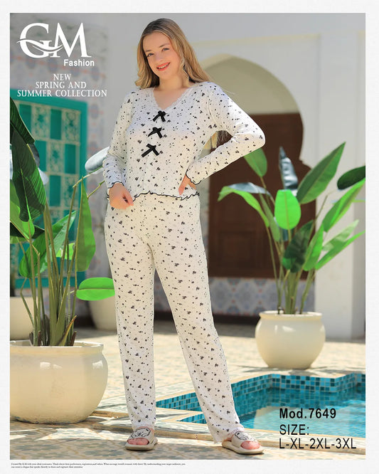Woman wearing a patterned outfit by GM Fashion by a poolside with plants.
